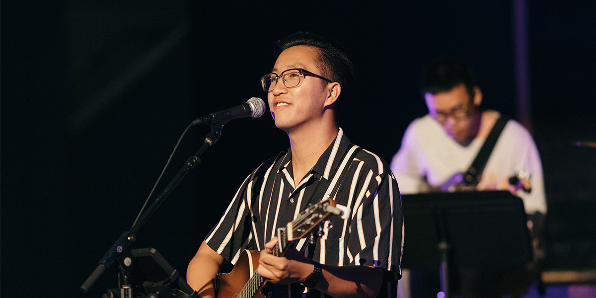 Brandon Li leads the crowd in worship while playing his guitar.
